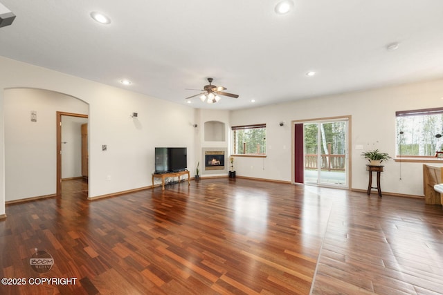 3600 N Fortune Cir, Wasilla, AK 99654 - unfurnished living room with arched walkways, recessed lighting, wood finished floors, ceiling fan, and a glass covered fireplace