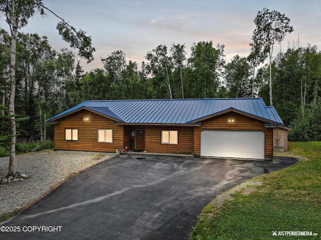 3600 N Fortune Cir, Wasilla, AK 99654 - rustic home featuring faux log siding, asphalt driveway, an attached garage, metal roof, and view of wooded area