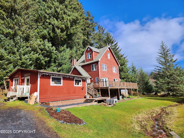 rear view of property with a wooden deck, a lawn, and a chimney