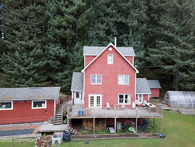 rear view of house featuring an exterior structure, an outbuilding, a shingled roof, and a deck