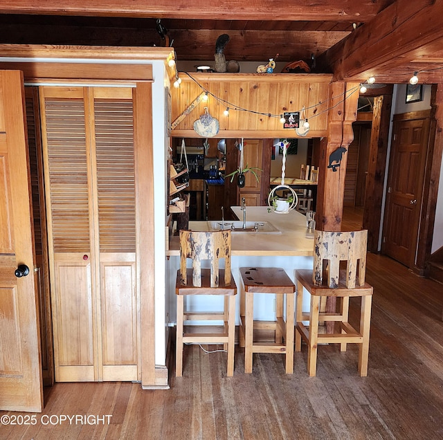 kitchen with hardwood / wood-style floors, a breakfast bar area, and beamed ceiling