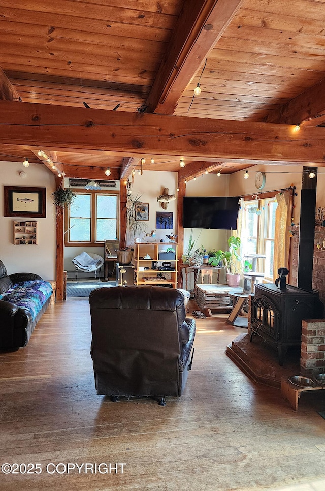 living area with wood finished floors, a wood stove, beam ceiling, and wooden ceiling