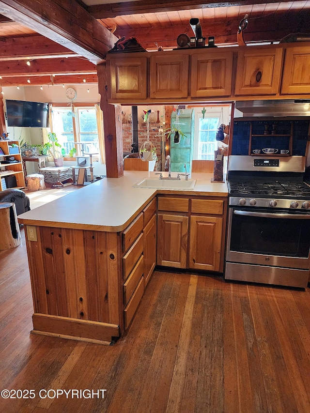 kitchen with beamed ceiling, stainless steel range with gas stovetop, dark wood-style floors, and a sink