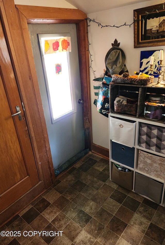 doorway with baseboards and stone tile flooring