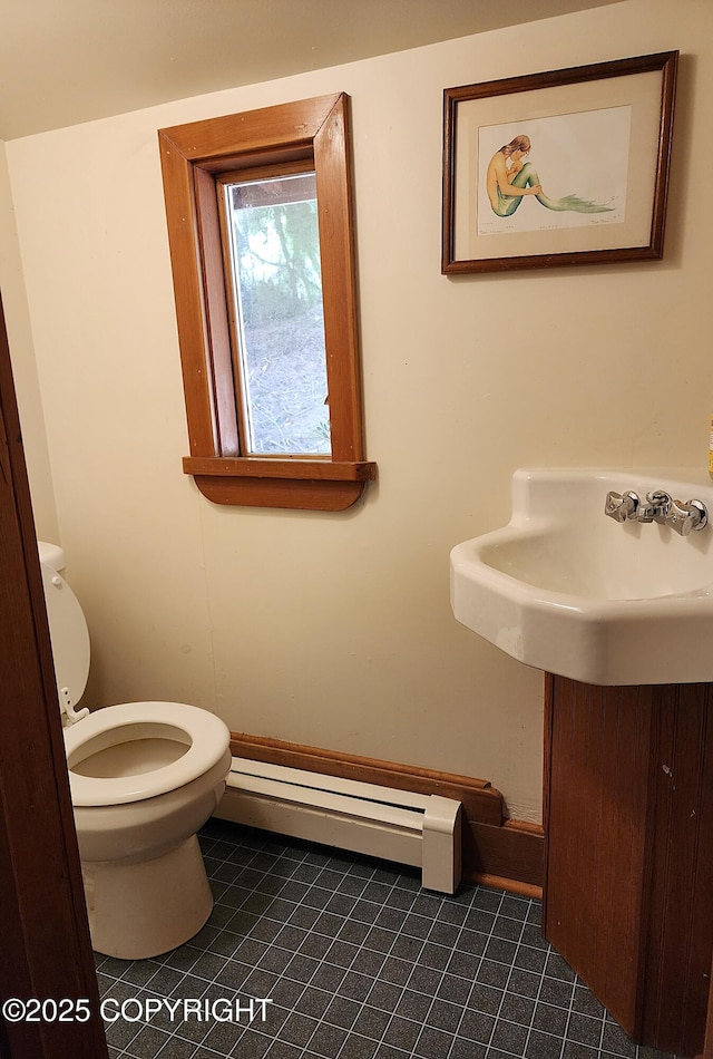 half bathroom with tile patterned floors, a baseboard radiator, and toilet