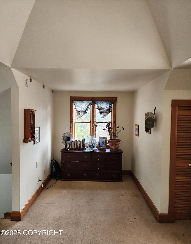 interior space featuring vaulted ceiling, baseboards, and light carpet