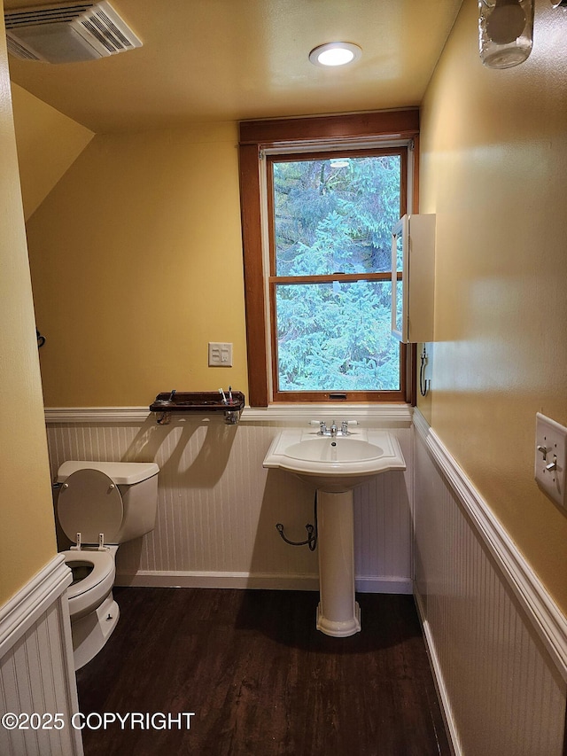 bathroom with wood finished floors, visible vents, toilet, and wainscoting