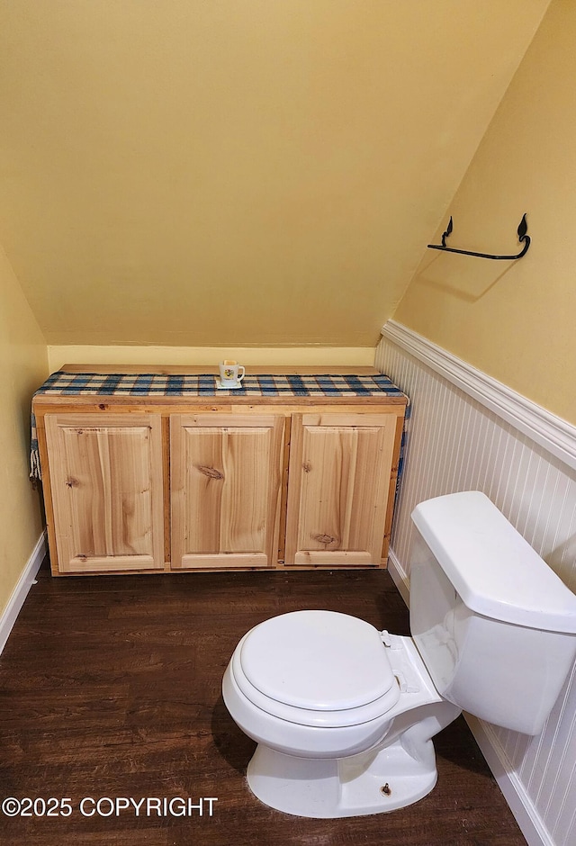 bathroom with wainscoting, wood finished floors, lofted ceiling, and toilet