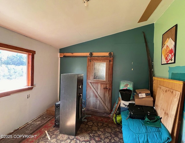 interior space with a barn door and vaulted ceiling