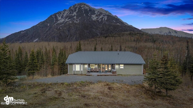 21899 Sterling Hwy, Cooper Landing, AK 99572 - back of property at dusk with metal roof, a deck with mountain view, and a view of trees
