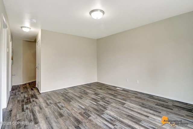 unfurnished room with wood finished floors, baseboards, and a smoke detector