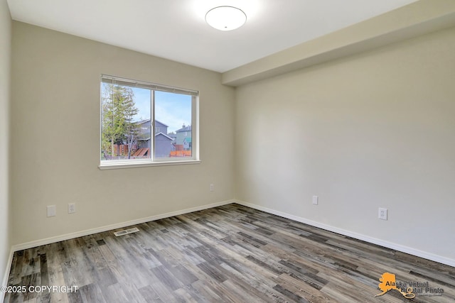 spare room featuring wood finished floors and baseboards