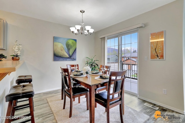 dining area with light wood-type flooring, a chandelier, and baseboards