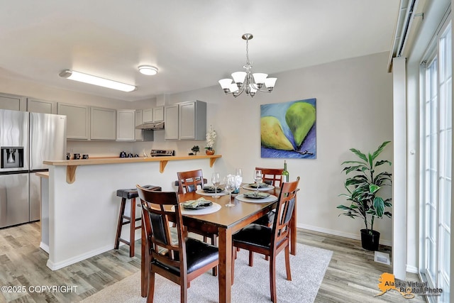 dining space with light wood-style flooring, a chandelier, and baseboards