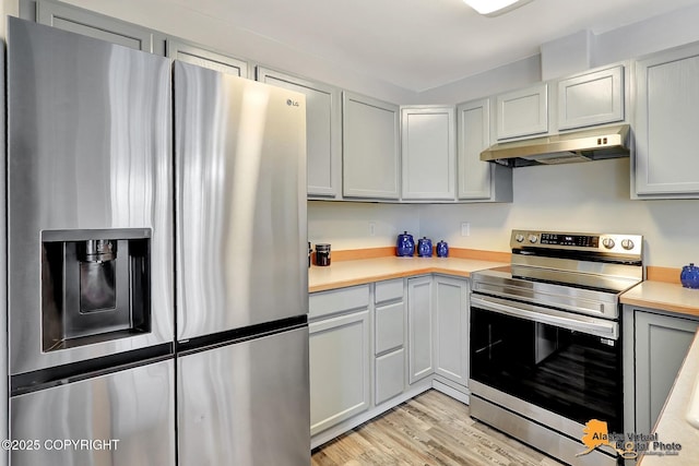 kitchen with appliances with stainless steel finishes, under cabinet range hood, light countertops, light wood-style floors, and gray cabinets