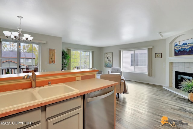 kitchen with dishwasher, a sink, open floor plan, a chandelier, and decorative light fixtures