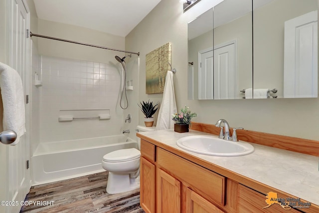 bathroom with wood finished floors, toilet, washtub / shower combination, and vanity