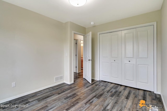 unfurnished bedroom with wood finished floors, baseboards, and a closet