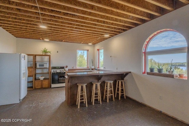 53160 Stol Rd, Clam Gulch, AK 99568 - kitchen with white appliances, a peninsula, and a kitchen bar