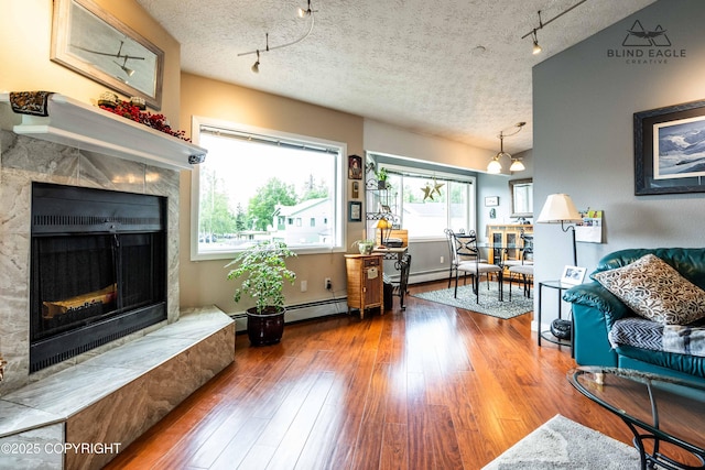 2000 Wenmatt Cir, Anchorage, AK 99517 - living room featuring rail lighting, a premium fireplace, wood-type flooring, a textured ceiling, and a baseboard heating unit