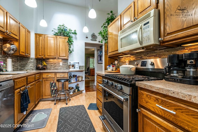 2000 Wenmatt Cir, Anchorage, AK 99517 - kitchen featuring stainless steel gas stove, white microwave, dishwasher, tasteful backsplash, and light wood-style floors