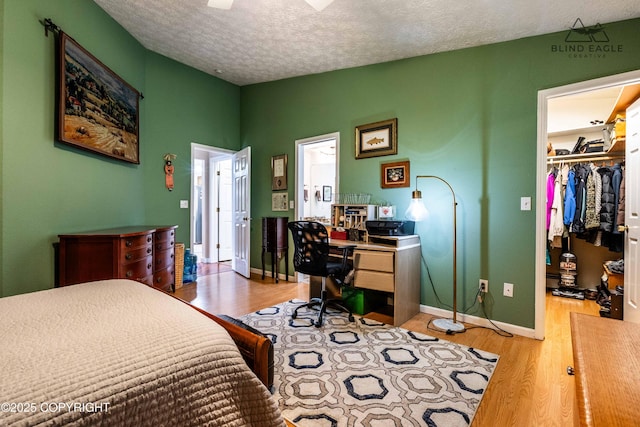 2000 Wenmatt Cir, Anchorage, AK 99517 - bedroom with a textured ceiling, wood finished floors, an office area, a walk in closet, and a closet