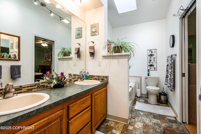 2000 Wenmatt Cir, Anchorage, AK 99517 - full bathroom featuring a skylight, double vanity, stone finish flooring, a ceiling fan, and backsplash