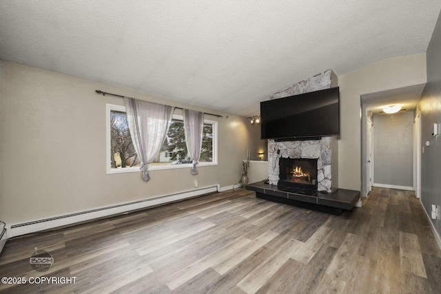1851 E 53rd Ave, Anchorage, AK 99507 - unfurnished living room featuring a textured ceiling, a stone fireplace, vaulted ceiling, wood finished floors, and a baseboard radiator