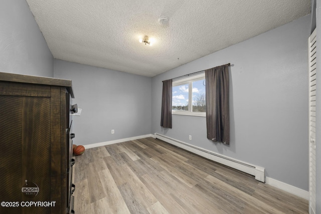 1851 E 53rd Ave, Anchorage, AK 99507 - unfurnished bedroom featuring a textured ceiling, baseboards, a baseboard heating unit, and wood finished floors