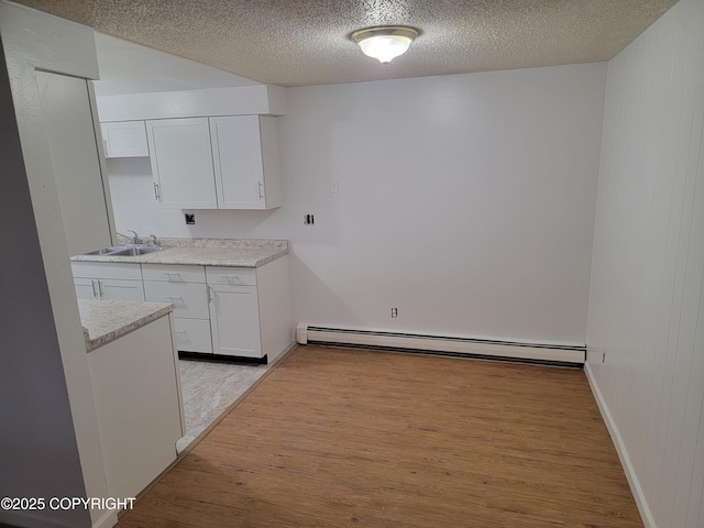 3505 Iowa St, Anchorage, AK 99517 - kitchen featuring a sink, light wood-style flooring, a textured ceiling, and baseboard heating
