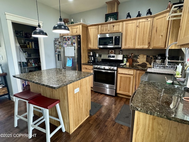 kitchen with pendant lighting, dark wood-style flooring, a kitchen bar, a center island, and stainless steel appliances