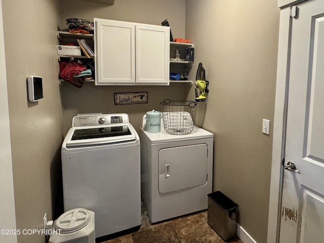 clothes washing area with baseboards, cabinet space, and washing machine and clothes dryer