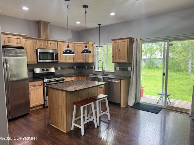 6230 N Crupperdock Dr, Palmer, AK 99645 - kitchen featuring appliances with stainless steel finishes, a center island, a kitchen breakfast bar, dark wood-style floors, and hanging light fixtures