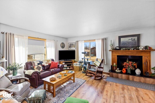 living room with plenty of natural light, wood finished floors, and a fireplace with raised hearth
