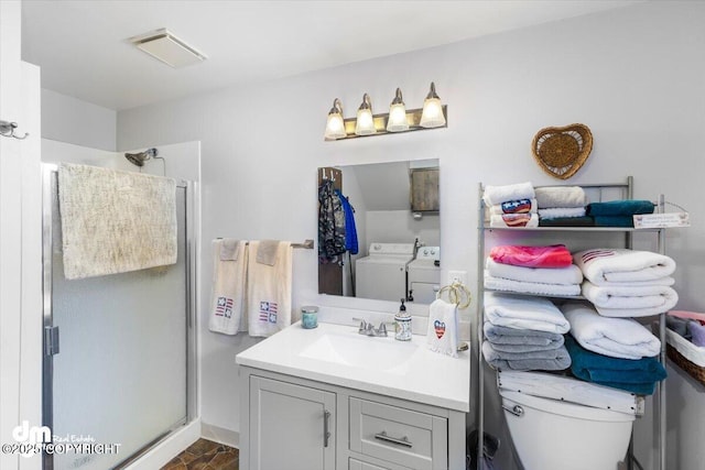 bathroom with vanity, washer and clothes dryer, a shower stall, and toilet