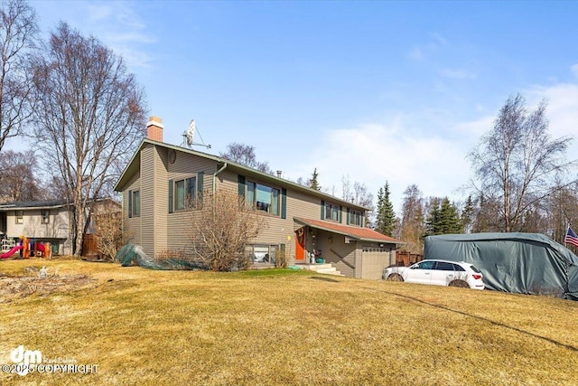 rear view of house featuring a garage, a yard, and a chimney