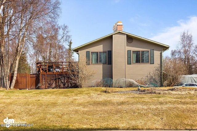 view of side of property with fence, a lawn, a chimney, and a deck