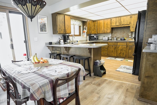 104 Beech Ave, Kenai, AK 99611 - kitchen featuring stainless steel microwave, brown cabinets, a peninsula, light wood-style floors, and light countertops