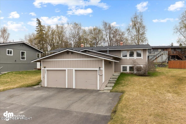 view of front of property with stairs, a garage, a front lawn, and driveway