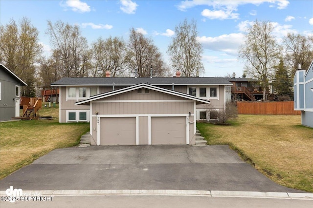 split foyer home featuring a shingled roof, a front lawn, and aphalt driveway