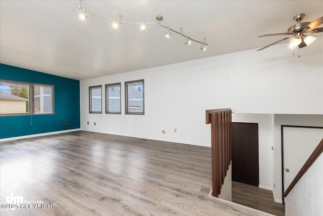 empty room featuring a ceiling fan, baseboards, track lighting, and wood finished floors