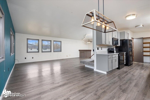 kitchen featuring wood finished floors, open floor plan, light countertops, a ceiling fan, and black appliances
