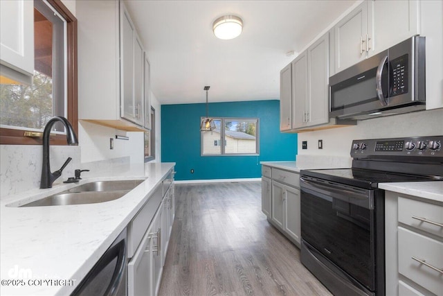 kitchen featuring wood finished floors, a sink, baseboards, stainless steel microwave, and black range with electric cooktop