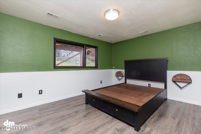 sitting room with visible vents, baseboards, and wood finished floors