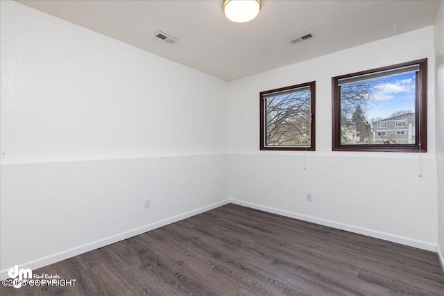 spare room featuring baseboards, visible vents, and dark wood-type flooring