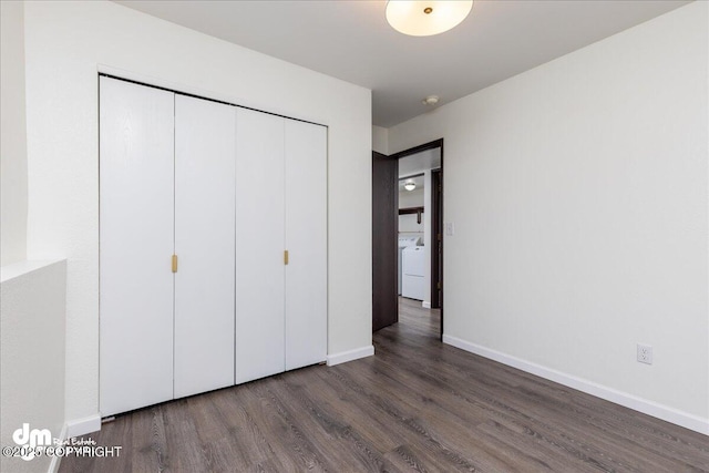 unfurnished bedroom featuring a closet, baseboards, washer / dryer, and wood finished floors
