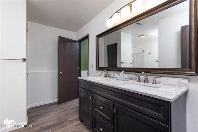 full bath featuring double vanity, visible vents, a sink, and wood finished floors