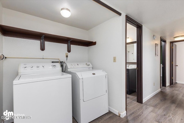 laundry area featuring independent washer and dryer, laundry area, baseboards, and wood finished floors