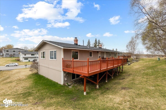 back of house featuring a lawn, a wooden deck, a shingled roof, and a chimney