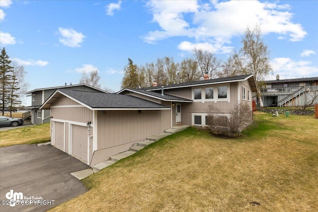 rear view of property featuring driveway, a chimney, roof with shingles, a yard, and an attached garage